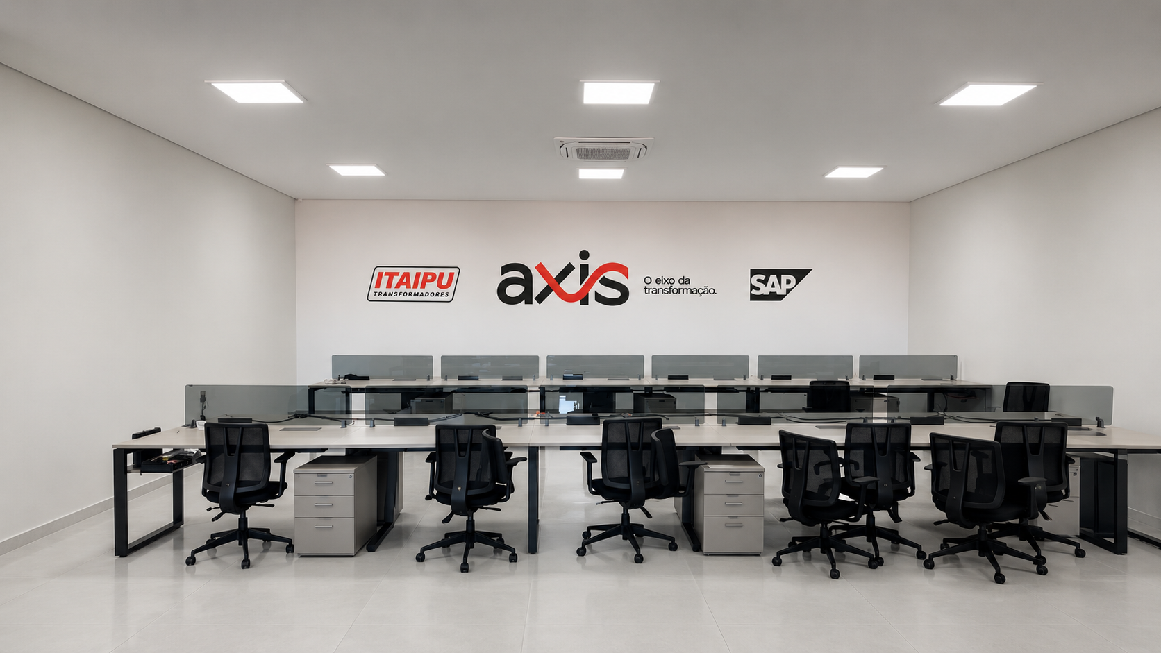 Sala do projeto AXIS com estacoes de trabalho e identidade visual na parede
